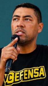 young Hispanic Latino man in VC Defensa T-shirt holds microphone